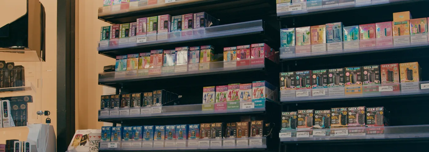 The vape wall: five shelves of disposable vapes behind the counter, brand by brand