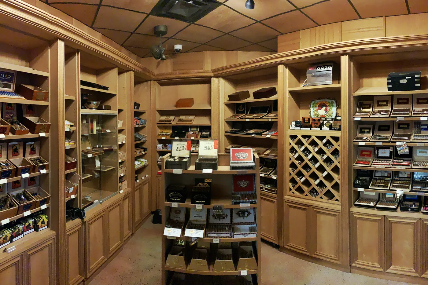 Inside the walk-in humidor: cedar shelving on three walls, a diamond lattice rack and a display case in the center of the room
