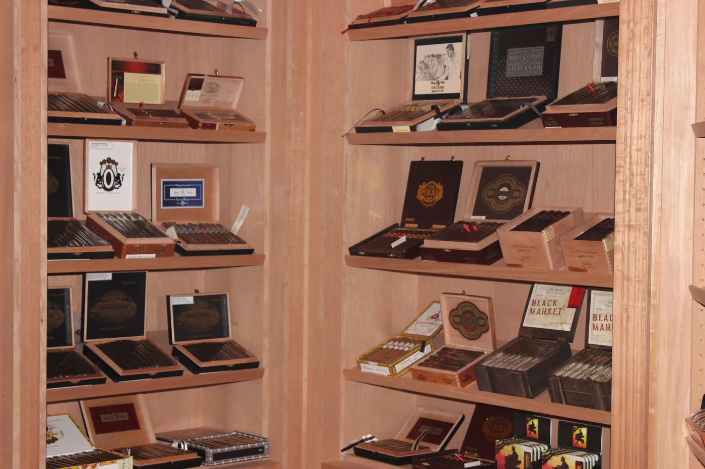 A full wall of the humidor, cedar shelves stacked with boxes and loose singles