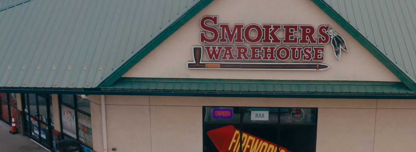 The Smoker's Warehouse storefront on Route 37: the sign under a green metal roof above a FIREWORKS SOLD HERE window