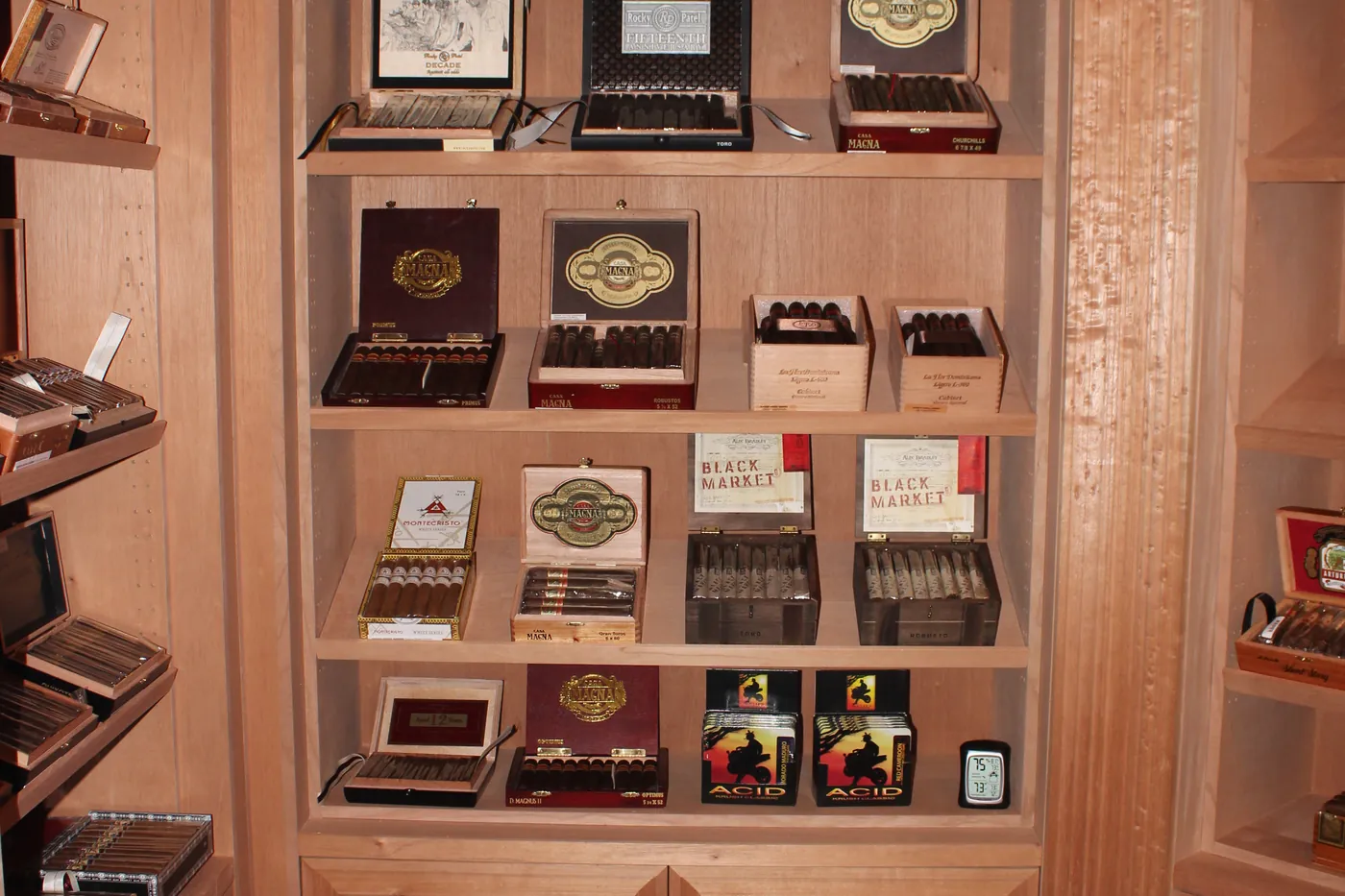 A wall inside the walk-in humidor, cedar shelving filled with open cigar boxes turned face out