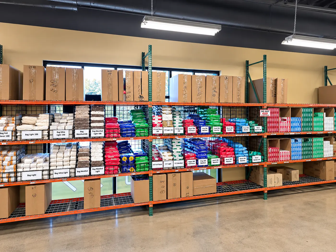 The bag wall inside the store: orange pallet racking three tiers high, every bay labeled by brand and style, stock boxes stacked along the top